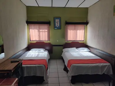 a room with two beds and a table and two windows at Hotel en Santa Ana in Santa Ana