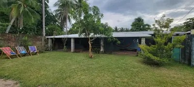 a yard with two chairs and a blue house at Kinta Mae Foster in Marcelino