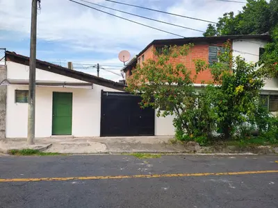 a white house with a green door on a street at Lombardia San Salvador City in San Salvador