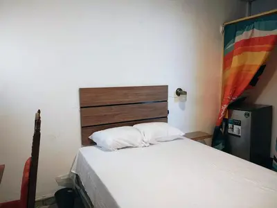 a bedroom with a bed with a wooden headboard at Lombardia San Salvador City in San Salvador