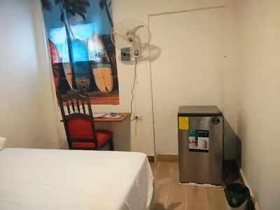 a room with a bed and a desk with a fan at Lombardia San Salvador City in San Salvador