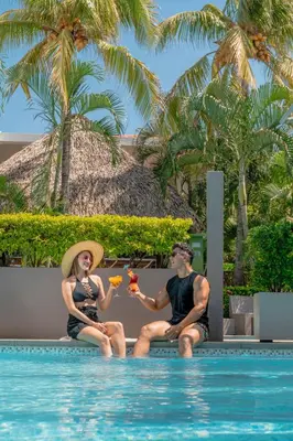 a man and a woman sitting next to a swimming pool at Hotel Roca Sunzal in La Libertad