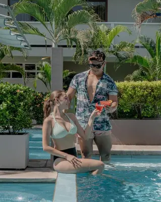 a man and a woman sitting next to a swimming pool at Hotel Roca Sunzal in La Libertad