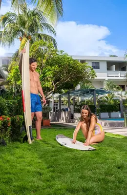 a man and a girl sitting on a surfboard in the grass at Hotel Roca Sunzal in La Libertad
