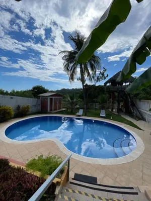 a large swimming pool in a yard with a palm tree at Casa de Playa en Atami, La Libertad, El Salvador in El Zonte