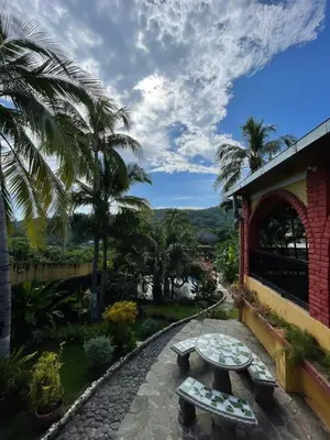 a patio with a table and benches and palm trees at Casa de Playa en Atami, La Libertad, El Salvador in El Zonte