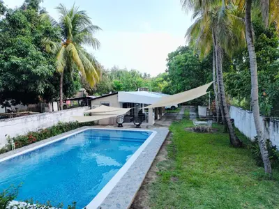a swimming pool next to a yard with palm trees at Casa de playa acogedora en San Diego, La Libertad, El Salvador in San Diego
