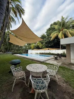 a table and chairs next to a swimming pool at Casa de playa acogedora en San Diego, La Libertad, El Salvador in San Diego