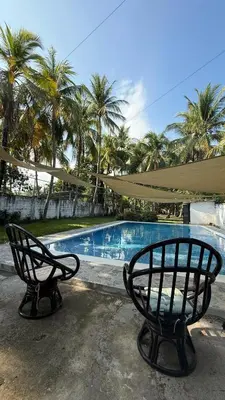 two benches sitting next to a swimming pool with palm trees at Casa de playa acogedora en San Diego, La Libertad, El Salvador in San Diego
