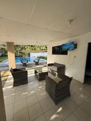 a patio with wicker chairs and a tv on the wall at Casa de playa acogedora en San Diego, La Libertad, El Salvador in San Diego