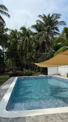 a swimming pool with a umbrella and palm trees at Casa de playa acogedora en San Diego, La Libertad, El Salvador in San Diego