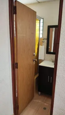 a bathroom with a door and a sink and a mirror at Lombardia Planes de Renderos in San Marcos