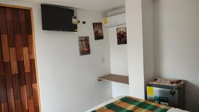 a room with a bed and a tv on a wall at Lombardia Planes de Renderos in San Marcos