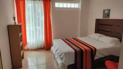 a bedroom with a bed and a window with orange curtains at Lombardia Planes de Renderos in San Marcos
