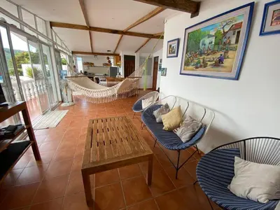 a living room with chairs and a table and a hammock at Mar y Cielo Beach House in Tamanique