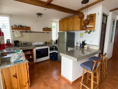 a kitchen with a refrigerator and a counter with stools at Mar y Cielo Beach House in Tamanique