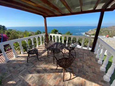 a porch with chairs and a view of the ocean at Mar y Cielo Beach House in Tamanique
