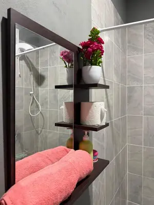 a bathroom with a mirror and pink towels and flowers at Milos Hostel in Santa Ana
