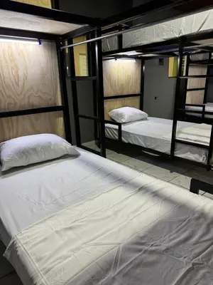 two bunk beds in a dorm room with white sheets at Milos Hostel in Santa Ana