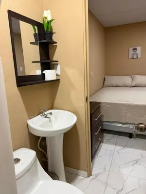 a bathroom with a sink and a toilet and a bed at Milos Hostel in Santa Ana