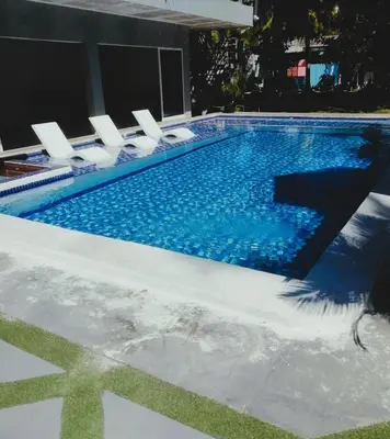a swimming pool with white chairs and a swimming pool at Kosta Brava Hotel y Restobar in El Majahual