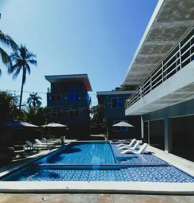 a swimming pool with lounge chairs and a building at Kosta Brava Hotel y Restobar in El Majahual