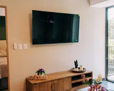 a living room with a flat screen tv on the wall at NEW Cozy&Modern Apt 30min from SurfCity in Hacienda Plan de La Laguna