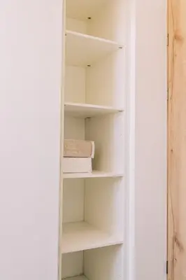 a white book shelf in a room at NEW Cozy&Modern Apt 30min from SurfCity in Hacienda Plan de La Laguna