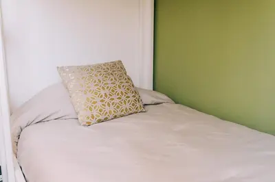 a white bed with a pillow on top of it at NEW Cozy&Modern Apt 30min from SurfCity in Hacienda Plan de La Laguna
