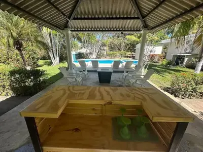 a wooden table in front of a swimming pool at Game Room • Pool • Fire Pit • Resort Access in Los Cóbanos
