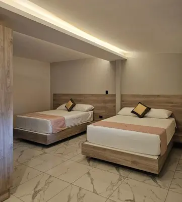 two beds in a large room withangular at Remfort Hotel Antigua in Santa Ana