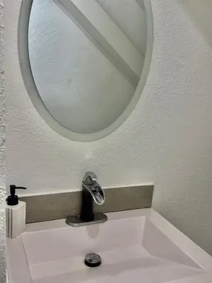 a bathroom sink with a round mirror above it at Atractivo apartamento in San Salvador