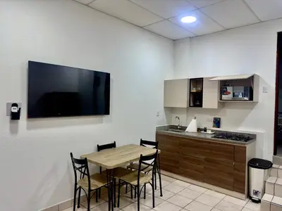 a kitchen with a table with chairs and a television on the wall at Atractivo apartamento in San Salvador
