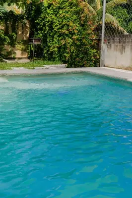 a large pool of blue water in a yard at Villa Palmarcito in El Zonte