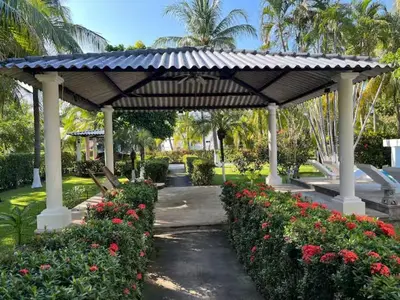 a pavilion with flowers in a park with palm trees at Pool • Game Room • Fire Pit • Resort Access in Los Cóbanos