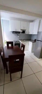 a kitchen with a table and chairs and a kitchen with white cabinets at Hogar cálido