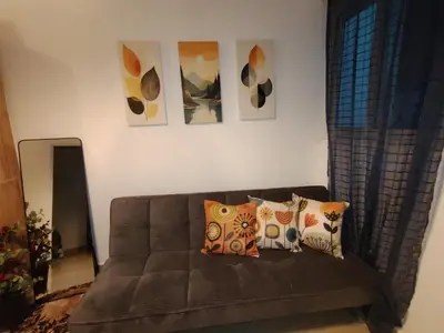 a couch in a living room with paintings on the wall at Casa Socorrito in Ahuachapán