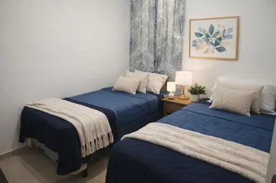 two beds in a room with blue sheets at Casa Socorrito in Ahuachapán