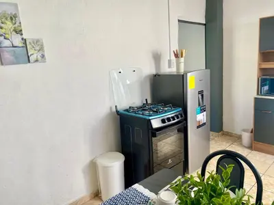 a kitchen with a stove and a refrigerator at Los Poca, Entire Home near Stadiums & Malls, San Salvador in San Salvador