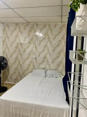 a white bed in a room with a wall at Los Poca, Entire Home near Stadiums & Malls, San Salvador in San Salvador