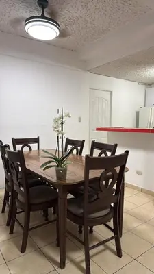 a dining room table with chairs and a vase with flowers at Hostal Proceres in San Salvador