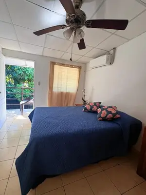 a bedroom with a blue bed with a ceiling fan at Hostal Proceres in San Salvador