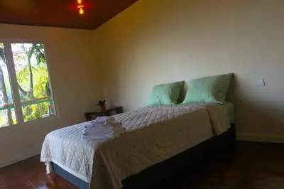 a bedroom with a bed with green pillows and a window at Cabañas y café Kauani