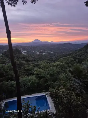 a view of a sunset from a resort with a swimming pool at Cabañas y café Kauani