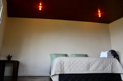 a bedroom with a bed with two green chairs at Cabañas y café Kauani