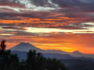 a sunset with a mountain in the background at Cabañas y café Kauani