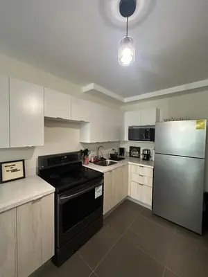 a kitchen with white cabinets and a black stove and refrigerator at NU Lomas Garden in Antiguo Cuscatlán