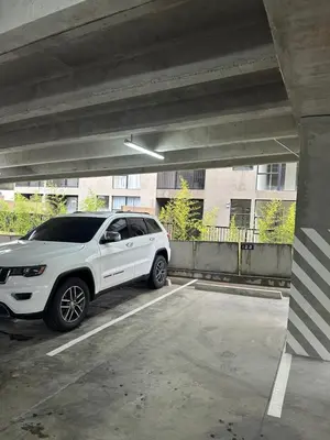 a white suv parked in a parking lot at NU Lomas Garden in Antiguo Cuscatlán