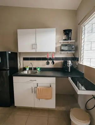 a small kitchen with white cabinets and a sink at Via Trip House - Sonsonate in Sonsonate
