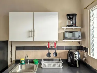 a kitchen with white cabinets and a sink and a microwave at Via Trip House - Sonsonate in Sonsonate